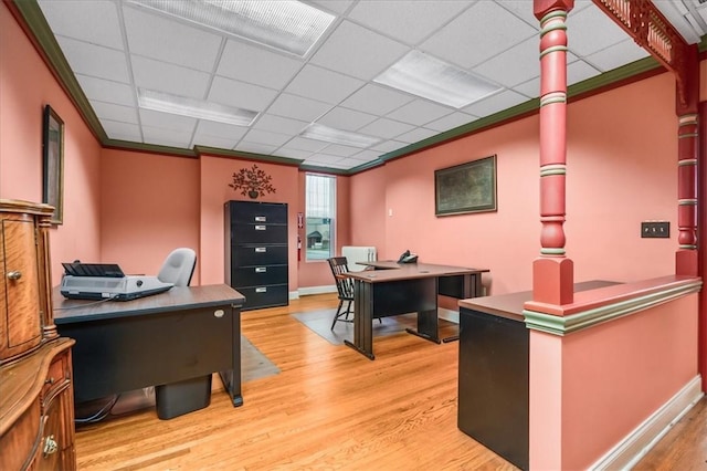 office space featuring ornamental molding, a drop ceiling, baseboards, and wood finished floors