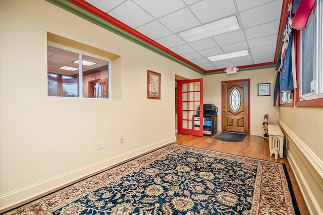 entrance foyer with light wood-type flooring, crown molding, baseboards, and a paneled ceiling