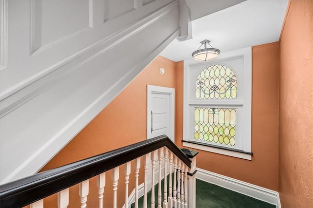 corridor with a textured wall, an upstairs landing, and baseboards