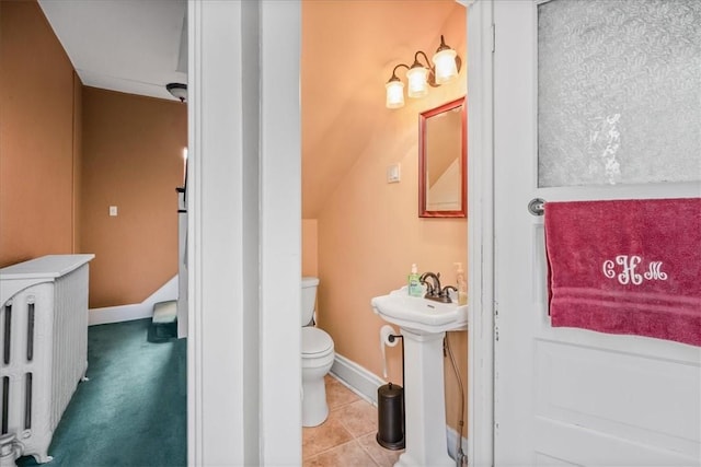 half bathroom with tile patterned flooring, toilet, a sink, baseboards, and radiator heating unit