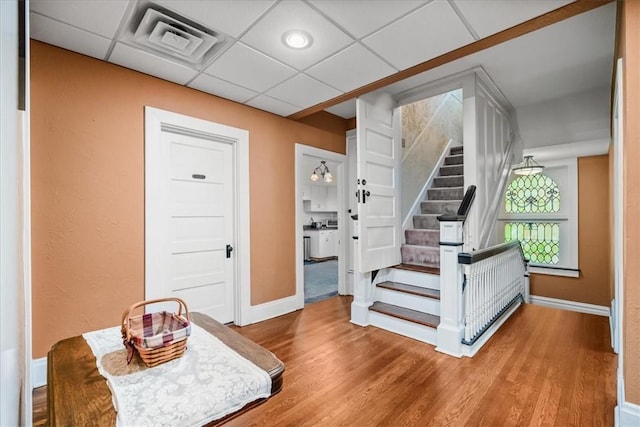 interior space featuring a paneled ceiling, visible vents, baseboards, and wood finished floors