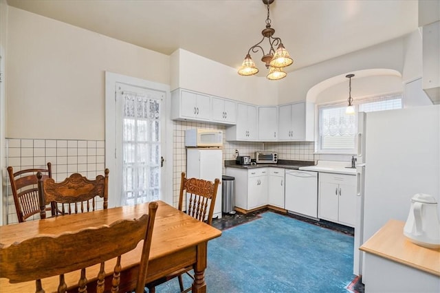 kitchen featuring white appliances, white cabinetry, decorative backsplash, dark countertops, and decorative light fixtures