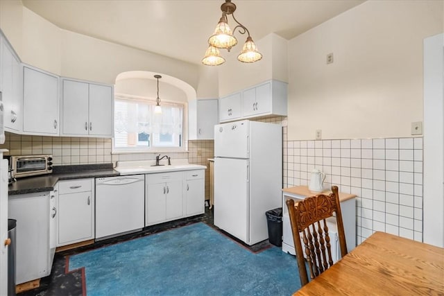 kitchen featuring dark countertops, white appliances, white cabinets, and hanging light fixtures