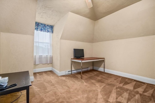 office area featuring lofted ceiling, baseboard heating, a ceiling fan, light carpet, and baseboards