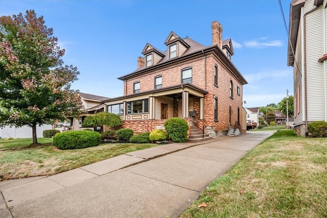 traditional style home with a chimney, a front lawn, and brick siding