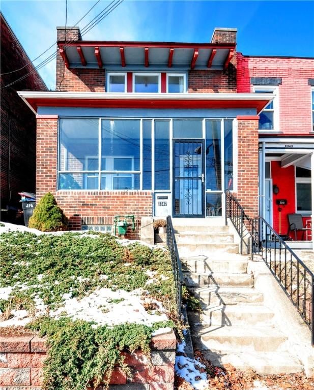 view of front of property featuring a sunroom, brick siding, and a chimney