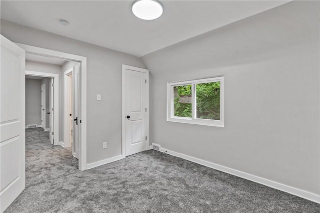 unfurnished bedroom featuring carpet, visible vents, vaulted ceiling, and baseboards