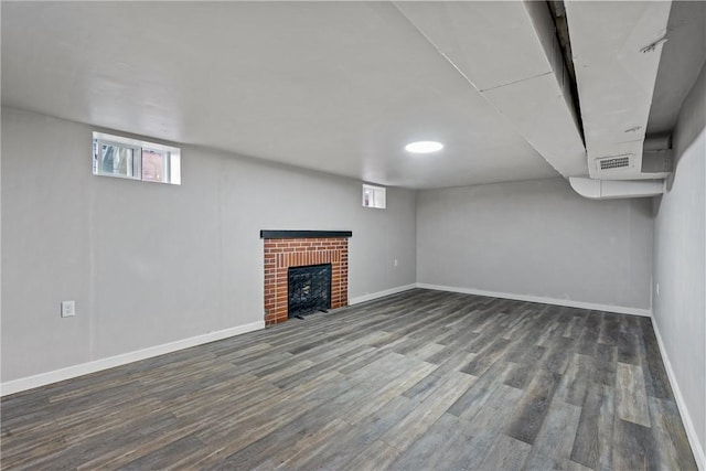 basement with a brick fireplace, visible vents, baseboards, and wood finished floors