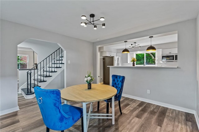 dining space with arched walkways, baseboards, and wood finished floors