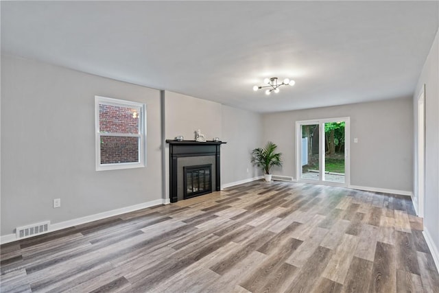 unfurnished living room featuring baseboards, a glass covered fireplace, visible vents, and light wood-style floors