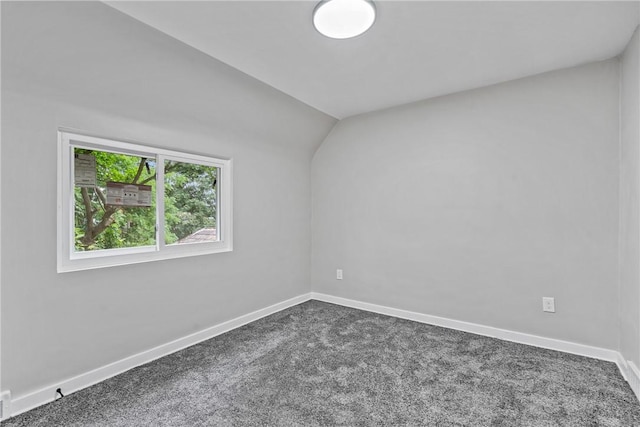 empty room featuring vaulted ceiling, carpet, and baseboards