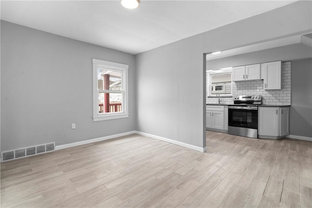 kitchen with dark countertops, visible vents, backsplash, electric range, and light wood-style floors