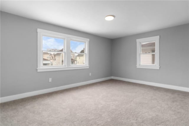 spare room featuring carpet floors, a healthy amount of sunlight, and baseboards