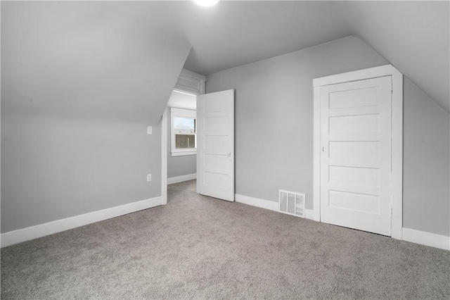 additional living space with baseboards, visible vents, vaulted ceiling, and carpet flooring