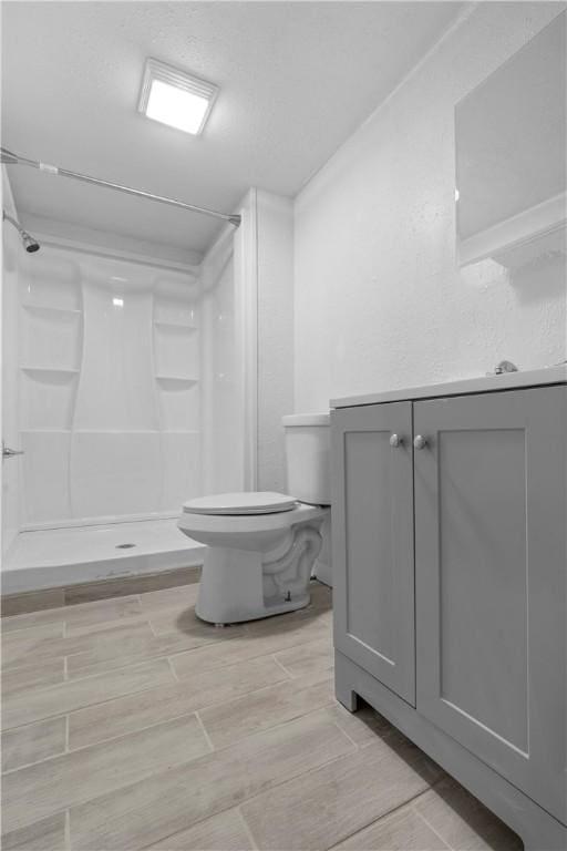 full bathroom with vanity, wood finish floors, a shower stall, and toilet