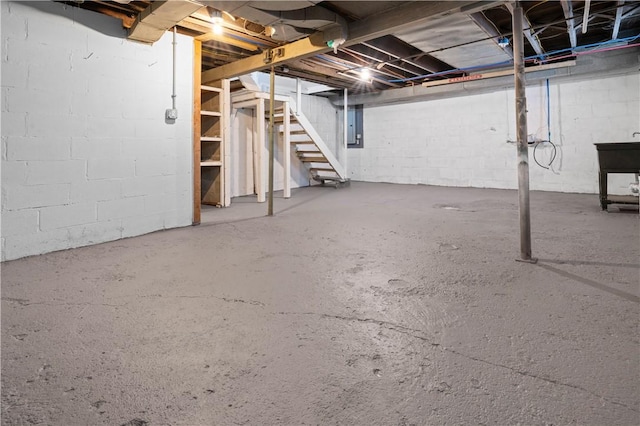 unfinished basement featuring stairs, a sink, and electric panel