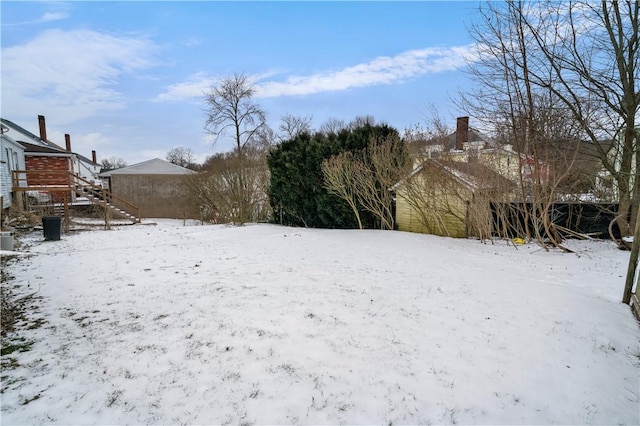 yard covered in snow featuring a detached garage and fence