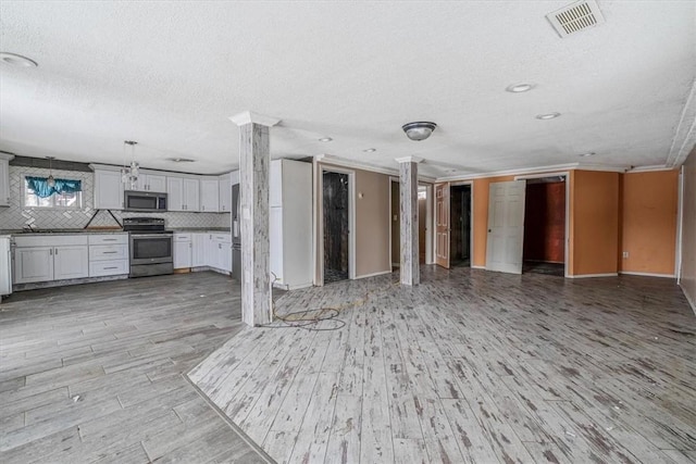 kitchen with visible vents, open floor plan, hanging light fixtures, stainless steel appliances, and white cabinetry