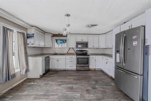 kitchen featuring stainless steel appliances, hanging light fixtures, visible vents, and white cabinets