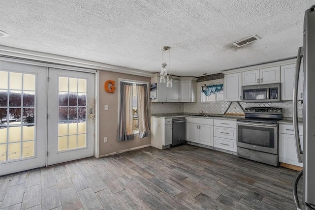 kitchen featuring visible vents, appliances with stainless steel finishes, decorative backsplash, dark wood-style floors, and decorative light fixtures