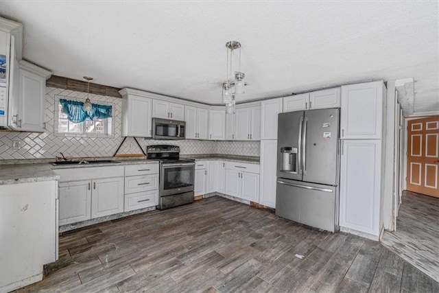 kitchen featuring stainless steel appliances, hanging light fixtures, light countertops, and white cabinets