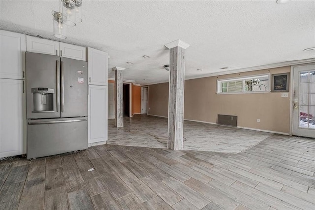 kitchen featuring ornate columns, white cabinets, light wood finished floors, and stainless steel fridge with ice dispenser