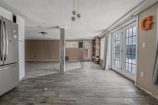 interior space with wood tiled floor, french doors, a textured ceiling, and baseboards