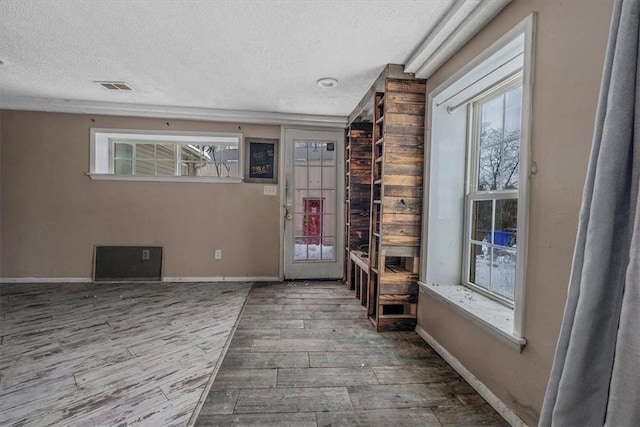 interior space featuring a textured ceiling, wood finished floors, visible vents, and baseboards