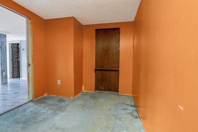 interior space featuring unfinished concrete floors and a textured ceiling