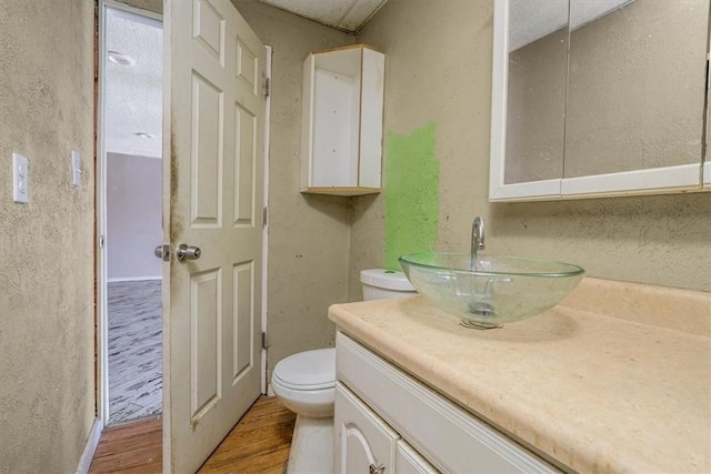 half bath featuring toilet, wood finished floors, and vanity