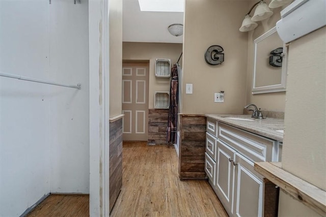 bathroom with a skylight, vanity, and wood finished floors