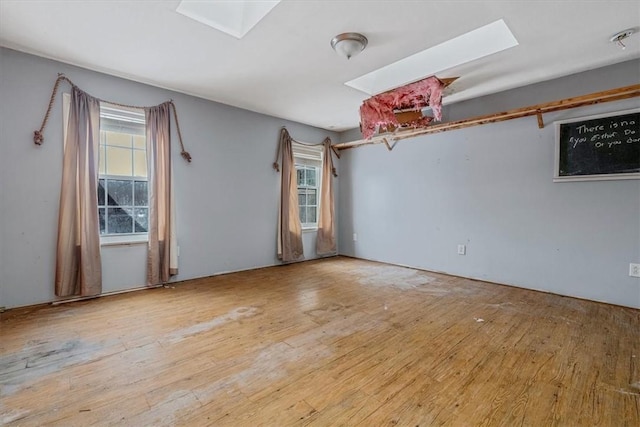 spare room with light wood-style floors and a skylight