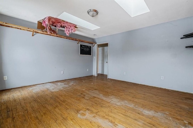 spare room with a skylight and wood finished floors