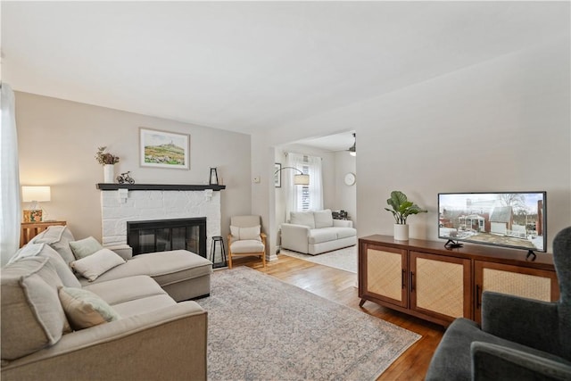 living room featuring a stone fireplace and wood finished floors