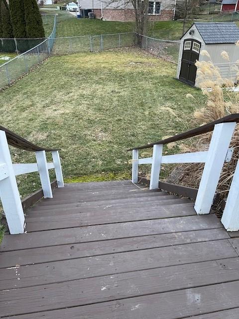 wooden deck featuring an outbuilding, a fenced backyard, a lawn, and a shed