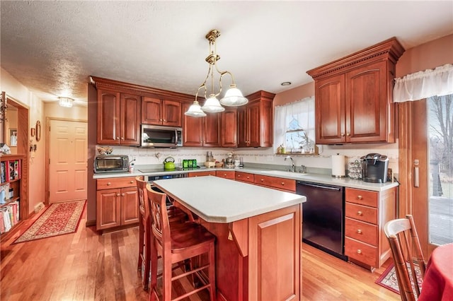 kitchen with dishwasher, stainless steel microwave, a center island, light countertops, and pendant lighting