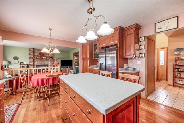 kitchen featuring a center island, pendant lighting, light wood finished floors, light countertops, and stainless steel fridge with ice dispenser