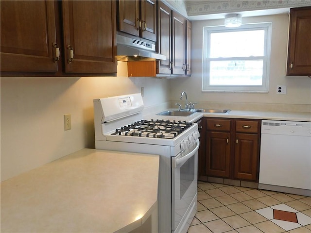 kitchen with white appliances, under cabinet range hood, a sink, light countertops, and light tile patterned floors