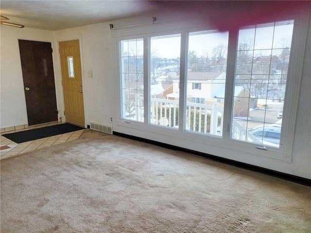 carpeted foyer with plenty of natural light, tile patterned flooring, and baseboards