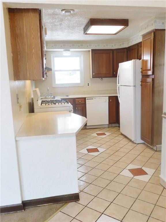 kitchen with white appliances, light countertops, a peninsula, light tile patterned flooring, and brown cabinetry