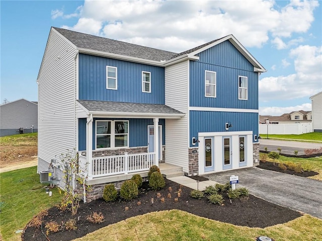 377 Leslie Farms Dr, Connoquenessing Boro, PA 16033 - modern farmhouse with driveway, stone siding, roof with shingles, a porch, and central AC