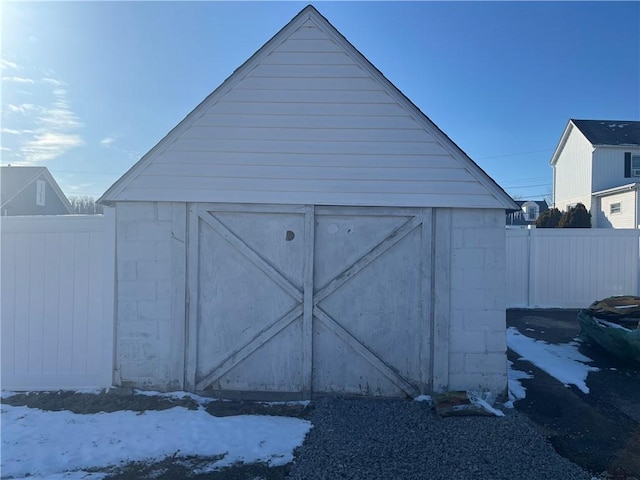 snow covered structure with an outbuilding, fence, and a storage shed