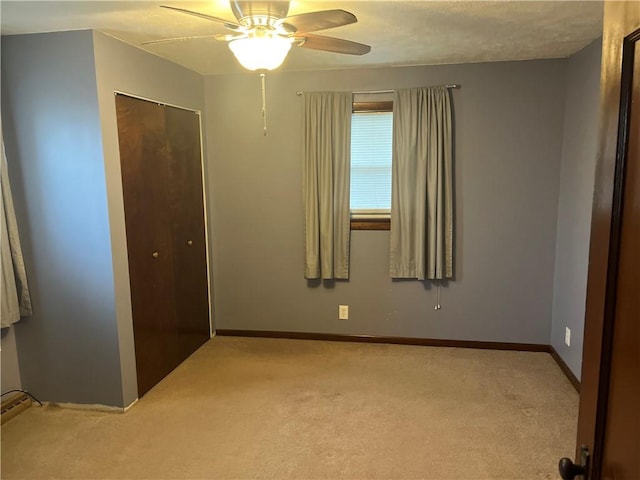 unfurnished bedroom featuring light carpet, ceiling fan, a closet, and baseboards