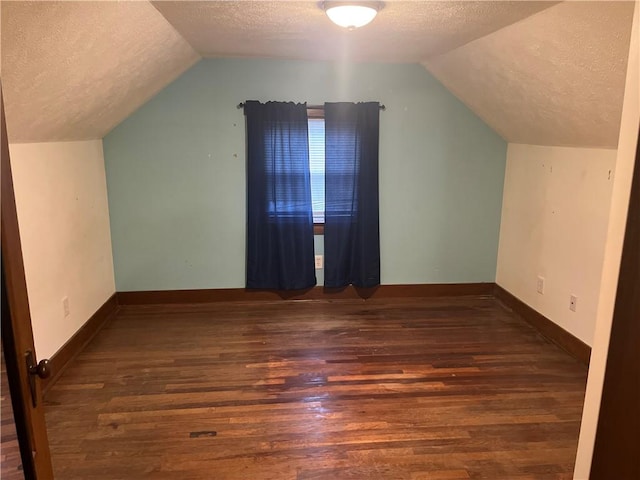 bonus room featuring dark wood-type flooring, vaulted ceiling, and a textured ceiling