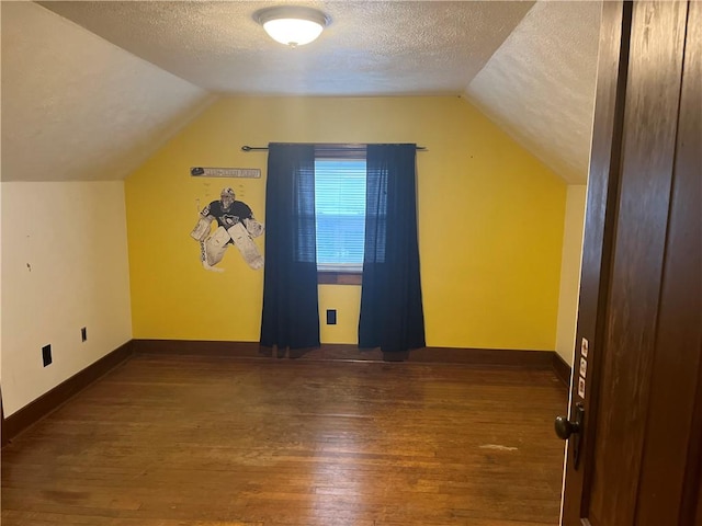 bonus room featuring a textured ceiling, dark wood-type flooring, lofted ceiling, and baseboards