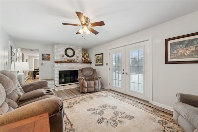 living area with a brick fireplace, french doors, baseboards, and wood finished floors