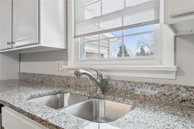 details with light stone countertops, white cabinets, and a sink