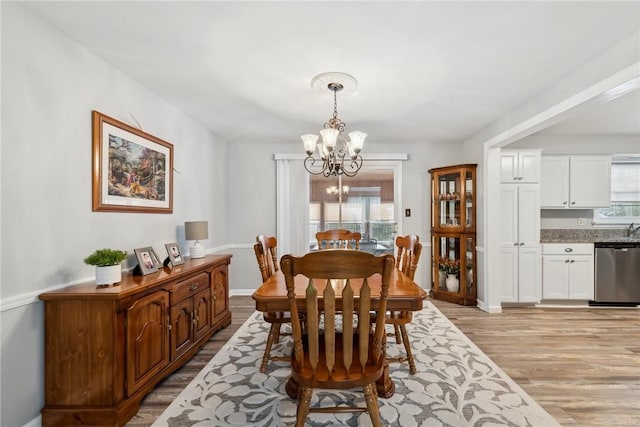 dining area with light wood finished floors, baseboards, and a chandelier