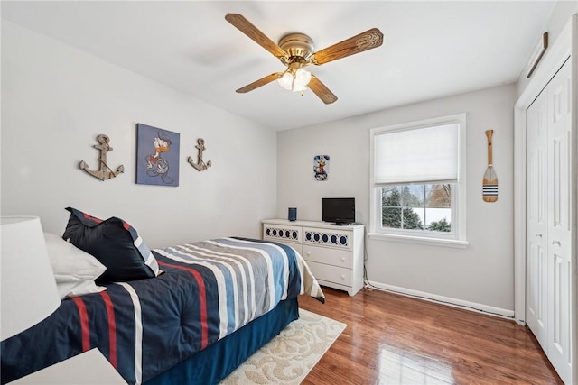 bedroom featuring a closet, wood finished floors, a ceiling fan, and baseboards