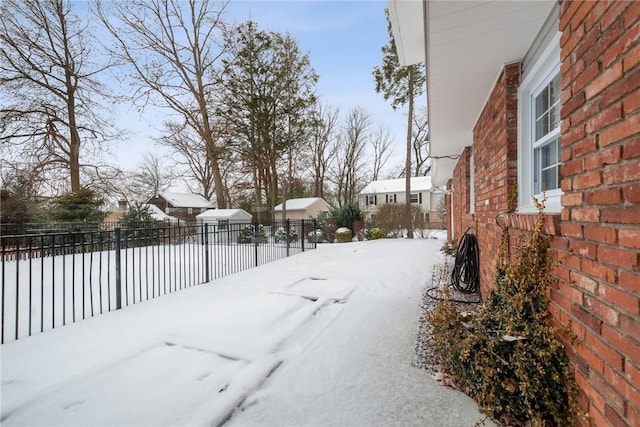 snowy yard featuring fence